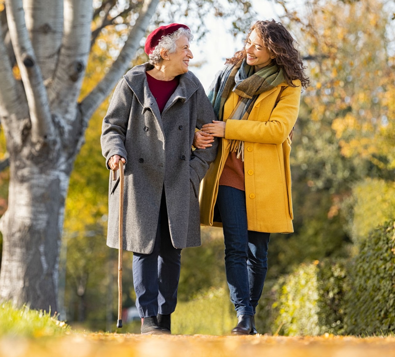 Junge und alte Frau spazieren durch eine herbstliche Landschaft